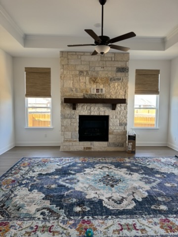 Natural woven wood shades frame this Kyle living space with warmth and texture, balancing natural light, privacy, and the clean architectural lines of the stone fireplace.