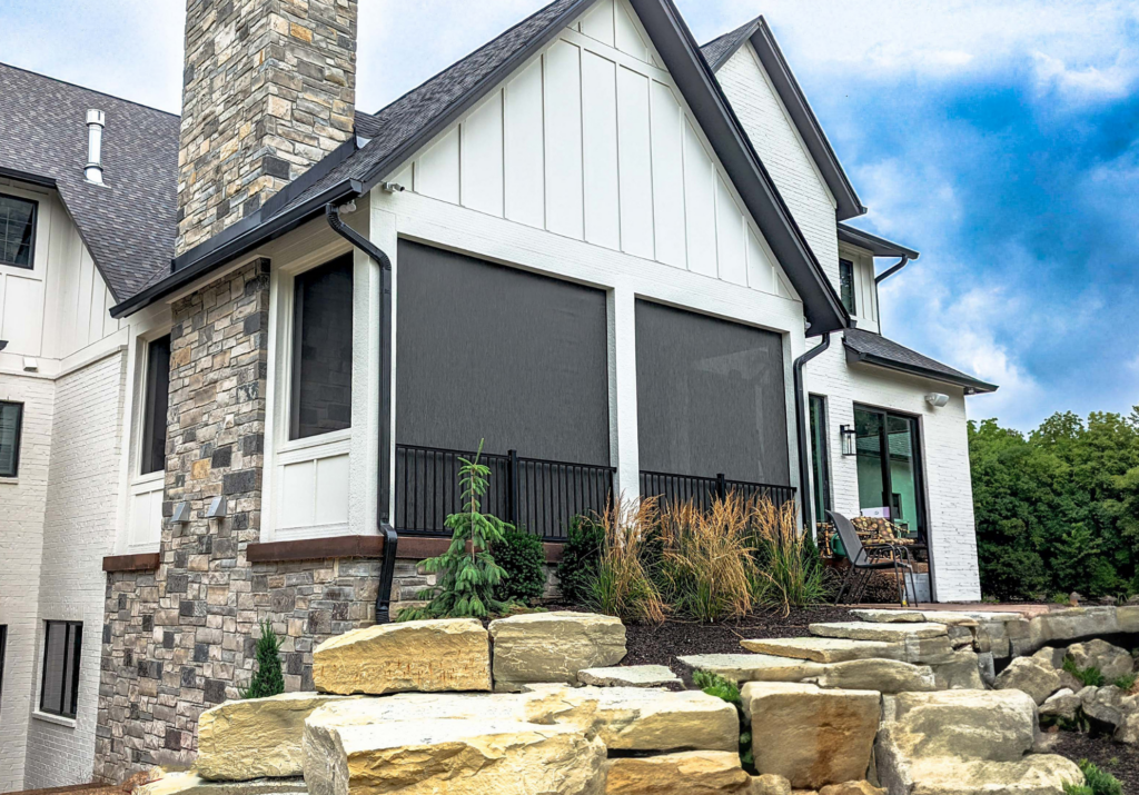 West facing patio shades  in Austin home with motorized exterior shades, large screened patio openings, stone fireplace accents, and modern outdoor living space for privacy, glare reduction, and sun control.