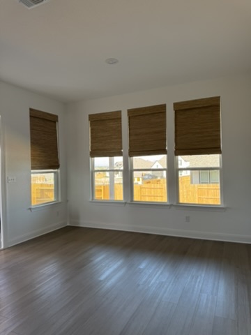 Natural woven shades in a Kyle, TX bedroom with multiple windows, combining privacy, natural light control, and warm organic texture.