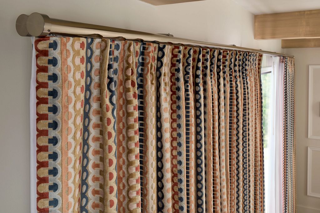 Custom patterned blackout curtains installed on a decorative rod, showcasing a layered window treatment approach often compared in blackout curtains vs blackout shades for light control and design impact.