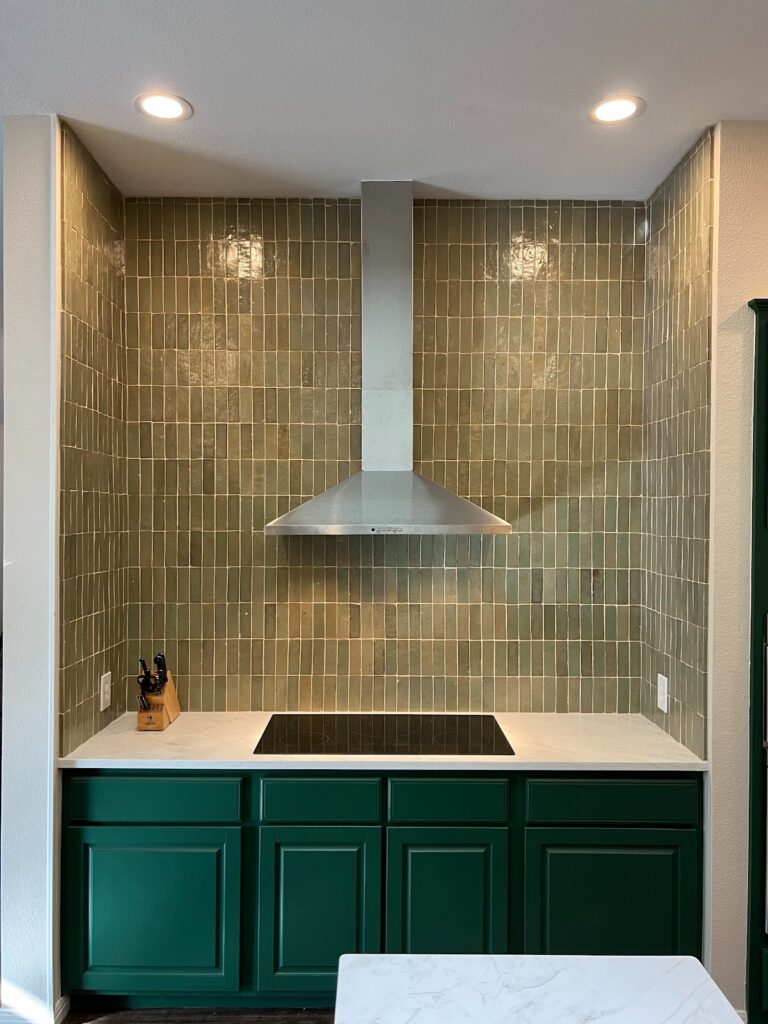 Georgetown kitchen nook with green cabinetry, glossy vertical tile backsplash, and stainless vent hood.