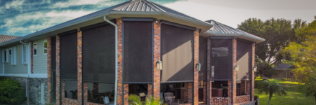 Motorized exterior shades installed between brick columns on a covered outdoor patio.