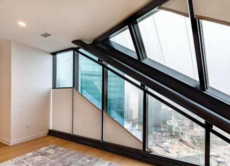 Hunter Douglas roller shades installed along angled glass windows in a high-rise stairwell.