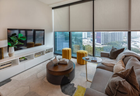 Hunter Douglas roller shades on floor-to-ceiling windows in a modern high-rise living room.
