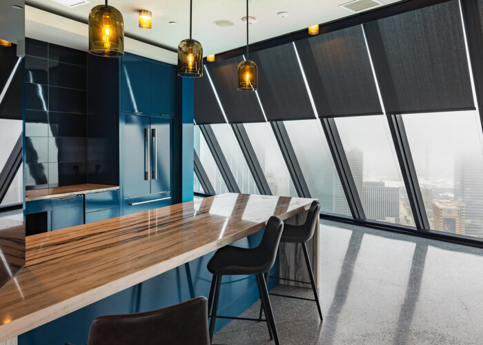 : Hunter Douglas dark roller shades on angled floor-to-ceiling windows in a modern kitchen space.