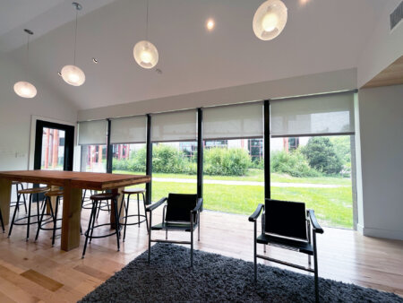 Hunter Douglas light-filtering roller shades on large windows in a modern lounge space.