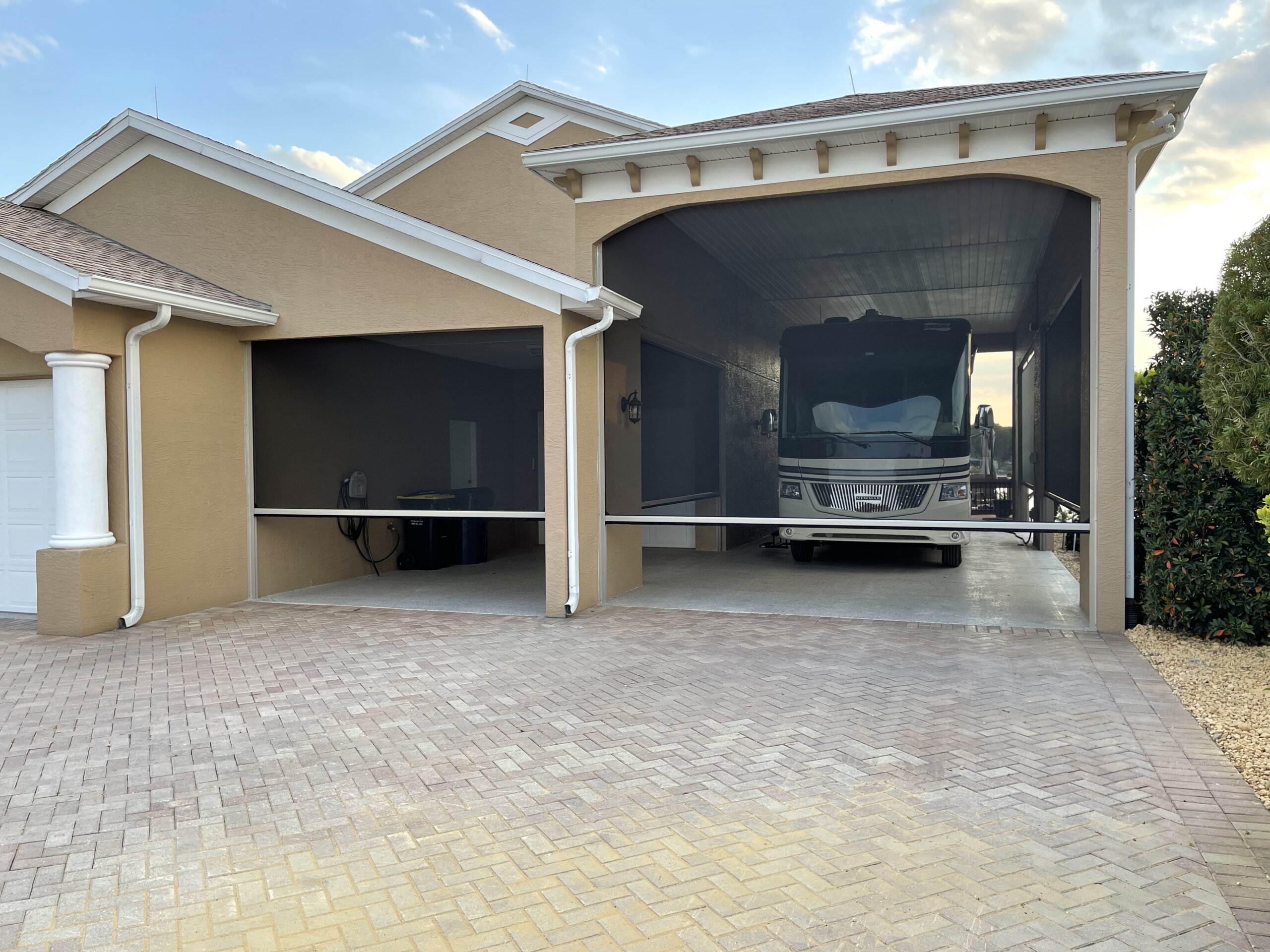Exterior shades on an Austin carport and garage area with stucco exterior, brick paver driveway, and RV parking.
