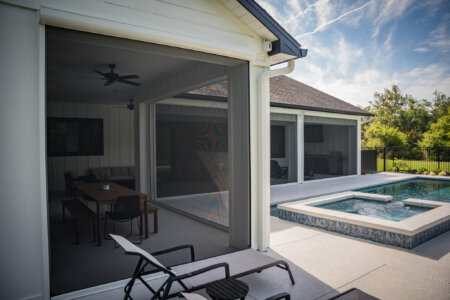Exterior shades on an Austin poolside patio with white siding, covered dining area, lounge chairs, and spa.