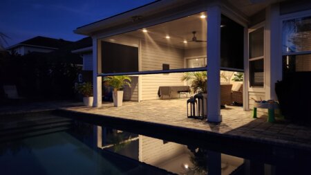 Exterior shades on an Austin poolside patio at night with covered seating, warm lighting, and backyard privacy.