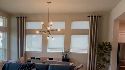 living room/ dining room with light filtering roller shades with drapery panels on each side