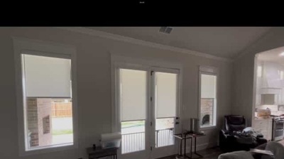 light filtering roller shades in white, in the living room along the back wall there are two windows as well as double doors