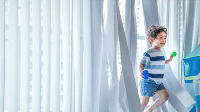white smart drapes with a child running through to show the movement of the smartdrapes