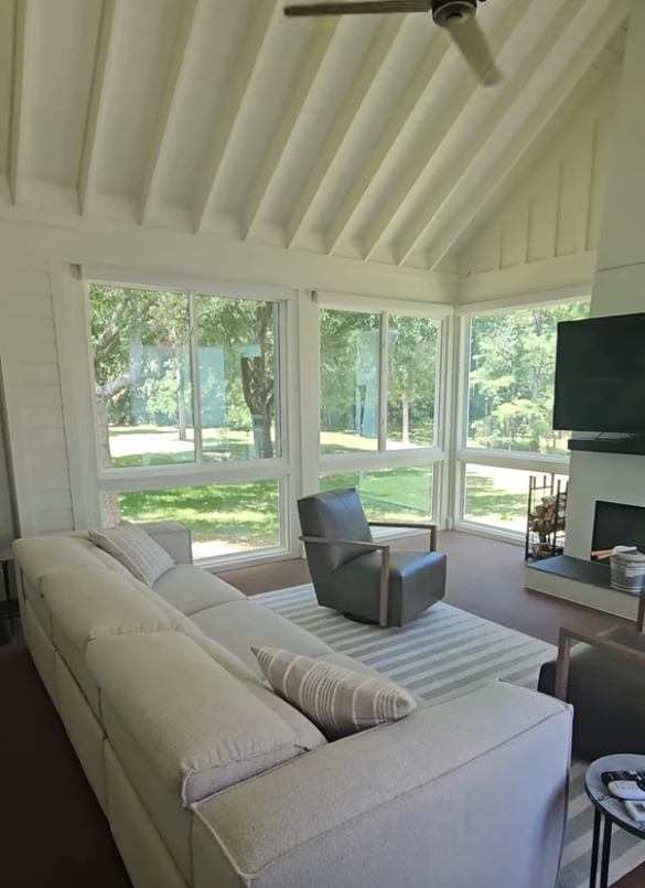A living room with open bright floor to ceiling windows,