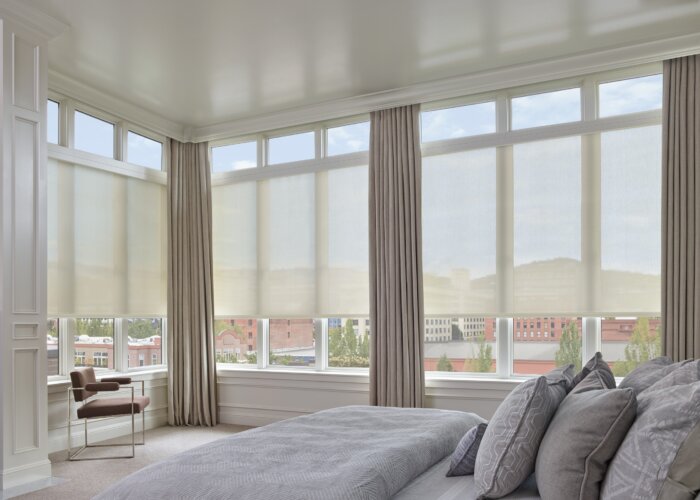 Light-filtering roller shades with custom drapery installed in a contemporary bedroom, showcasing premium custom window treatments for privacy and natural light control.