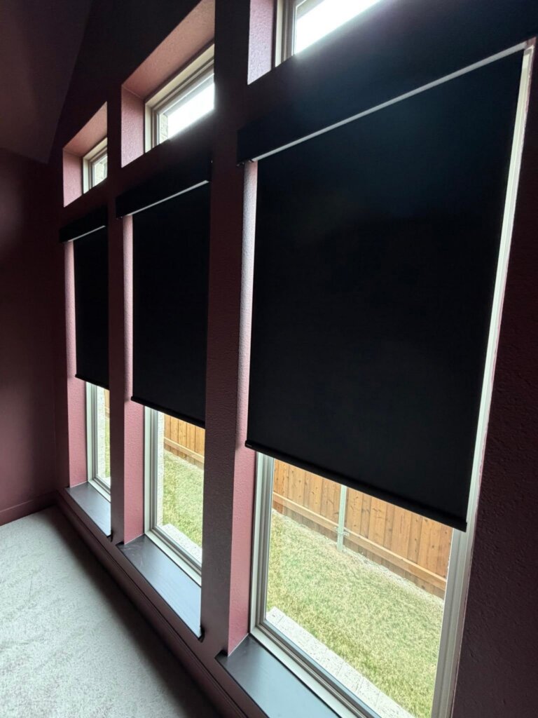 Blackout roller shades installed in a bedroom to block Texas heat and sunlight